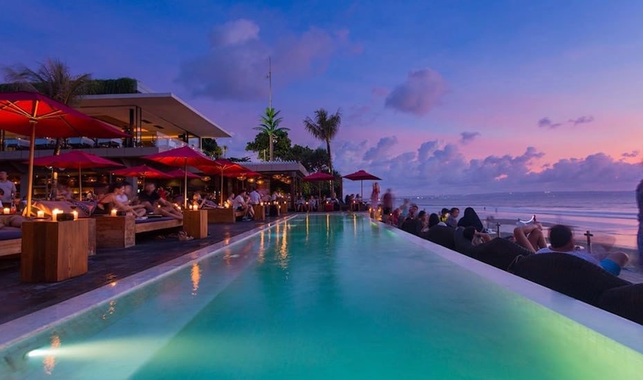 Beachfront infinity pool at sunset at KU DE TA Beach Club in Seminyak, Bali - Indonesia