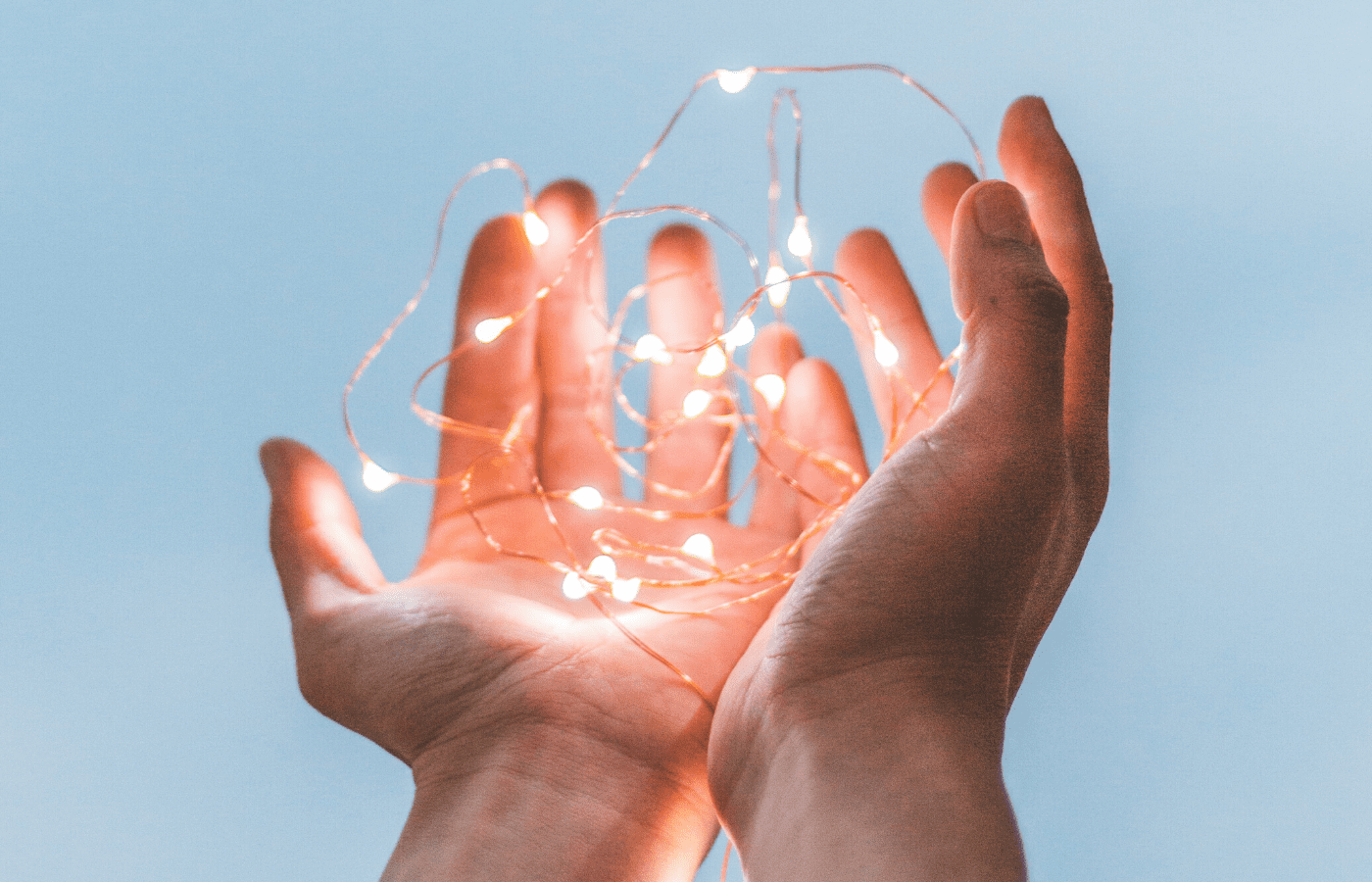 hands holding fairy lights | how to help covid-19